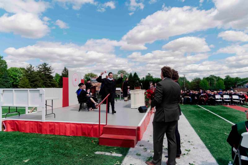 a man standing on a stage with a group of people in the background