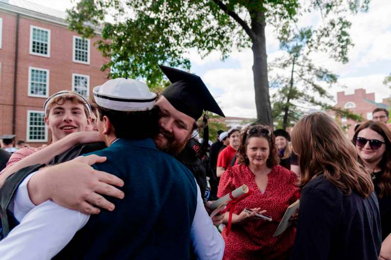 a man in a cap hugging a man in a graduation cap