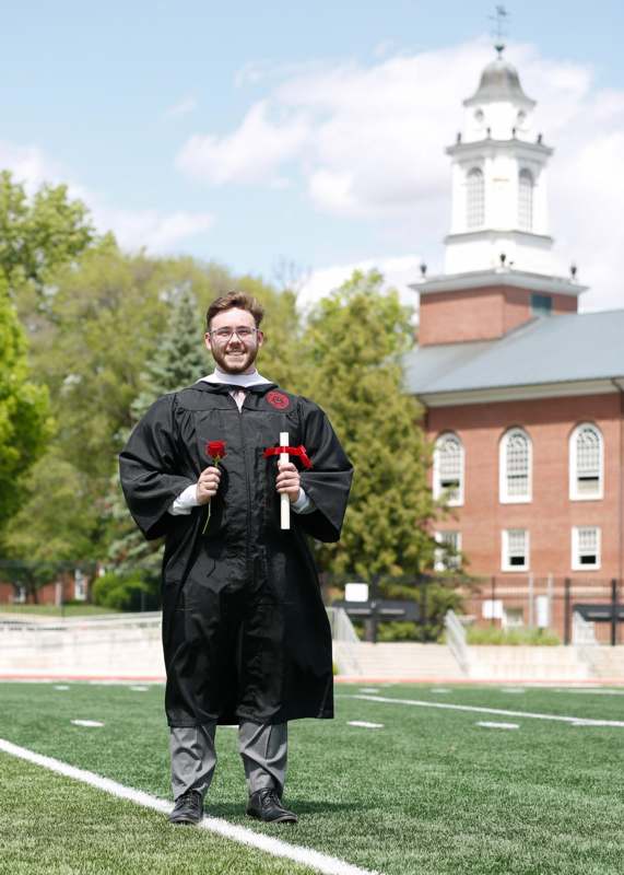 a man in a graduation gown holding roses