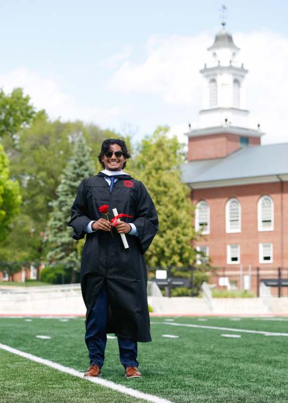 a man in a graduation gown holding a rose