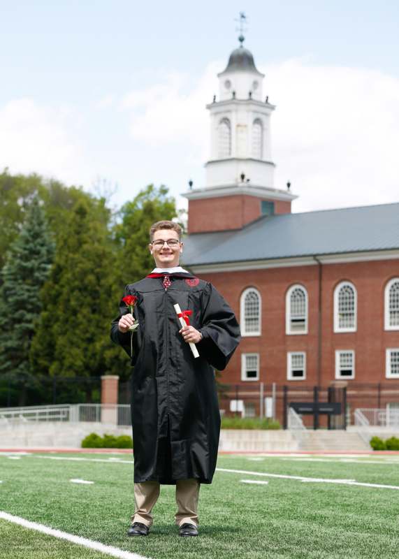 a man in a graduation gown holding flowers