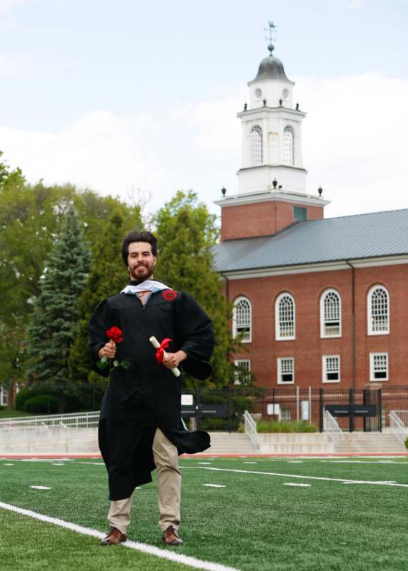 a man in a graduation gown holding flowers