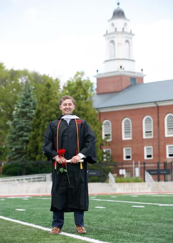 a man in a graduation gown holding a rose