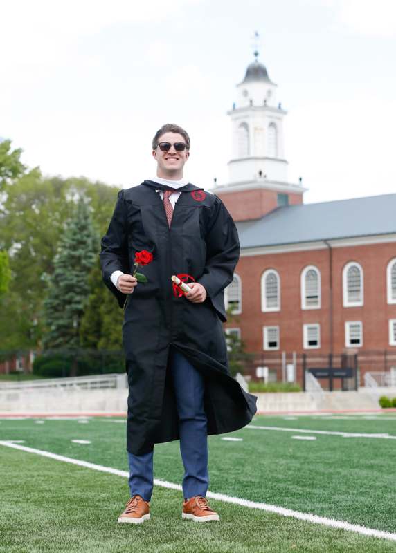 a man in a graduation gown holding a rose
