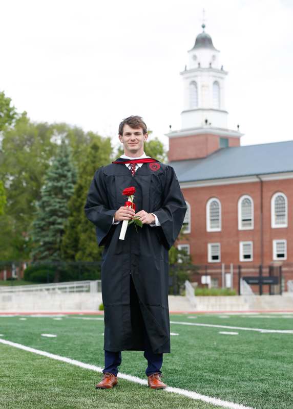a man in a graduation gown holding a rose