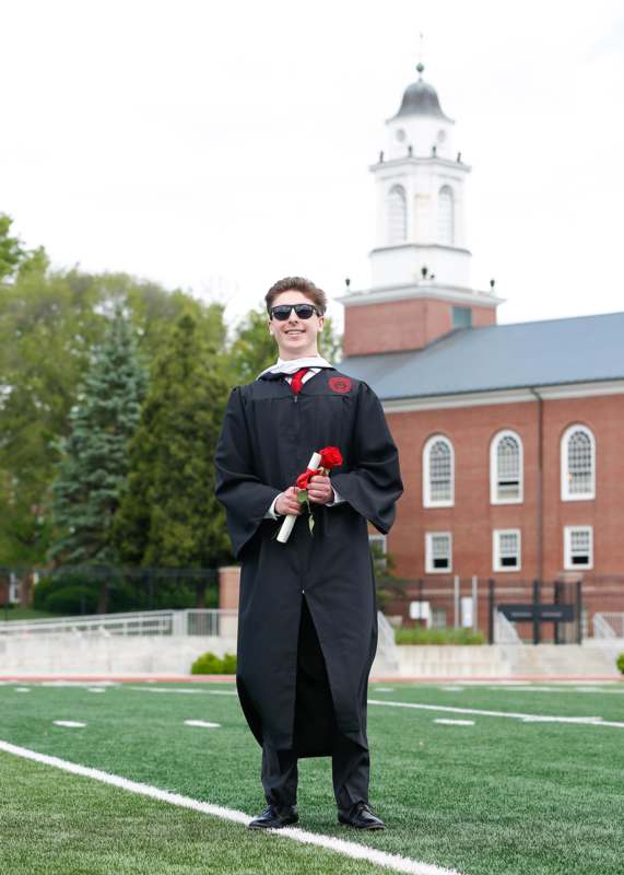 a man in a graduation gown holding a rose