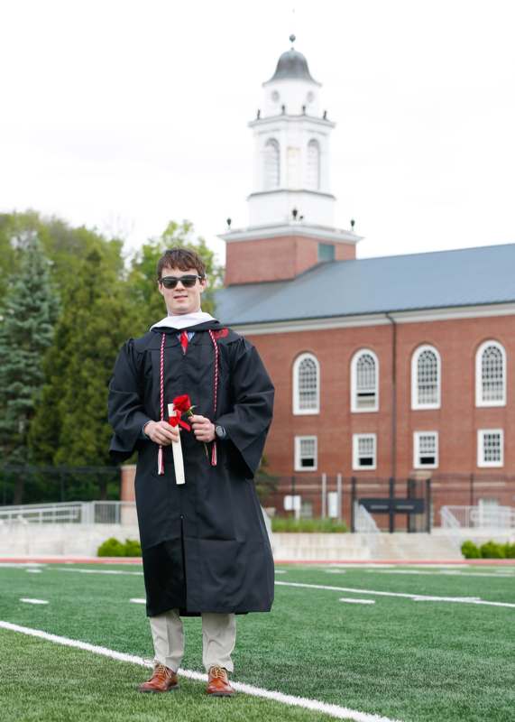 a man in a graduation gown holding a rose