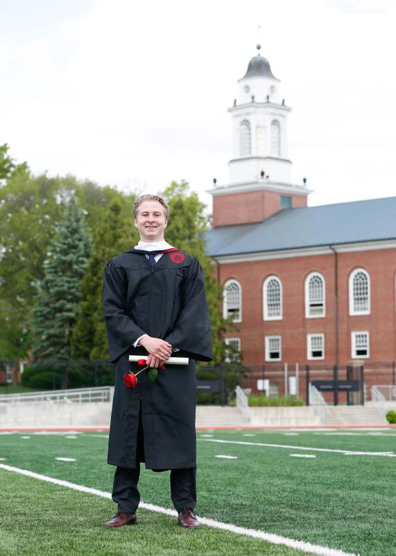 a man in a graduation gown holding a rose