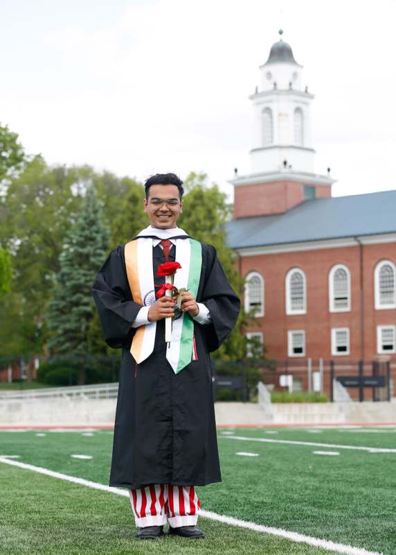 a man in a graduation gown holding a rose