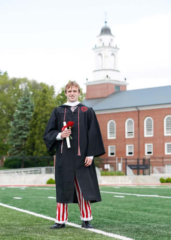 a man in a graduation gown holding a rose