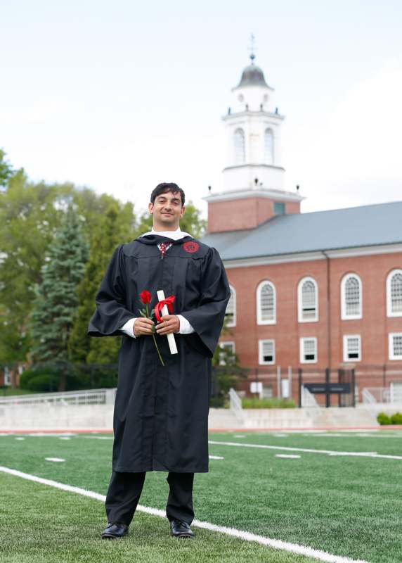 a man in a graduation gown holding flowers