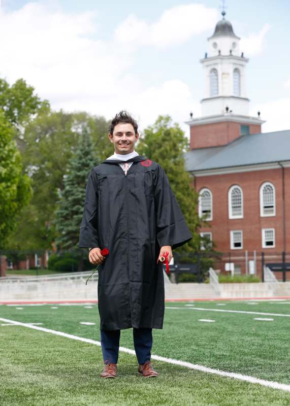 a man in a graduation gown holding flowers