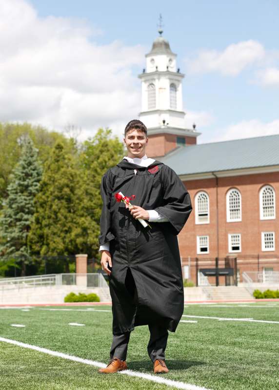 a man in a graduation gown holding a rose