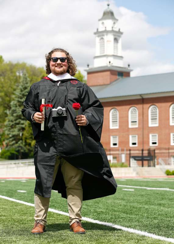 a man wearing a graduation gown and holding a rose