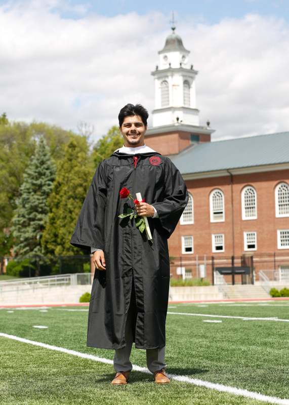 a man in a graduation gown holding a rose