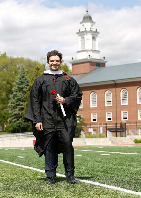 a man in a graduation gown holding a rose