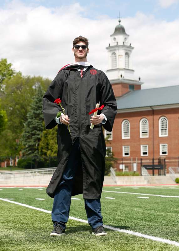 a man in a graduation gown holding flowers