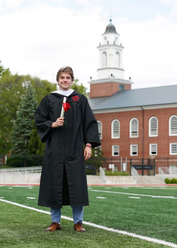 a man in a graduation gown holding a flower