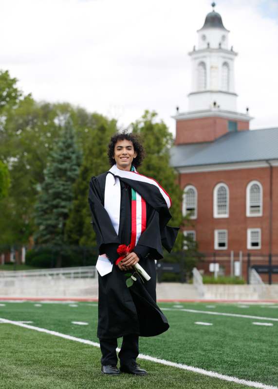 a man in a graduation gown holding a rose