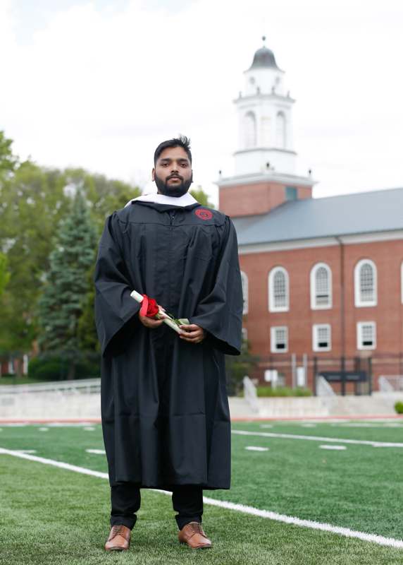 a man in a graduation gown holding a rose
