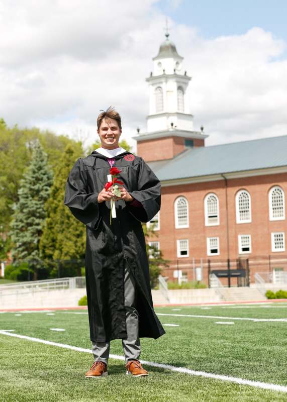 a man in a graduation gown holding flowers