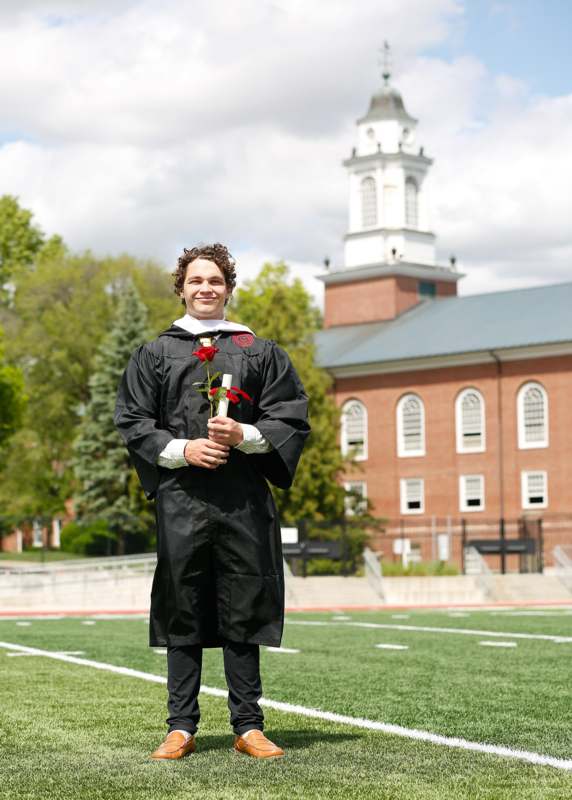 a man in a graduation gown holding a rose