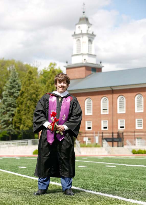 a man in a graduation gown holding flowers