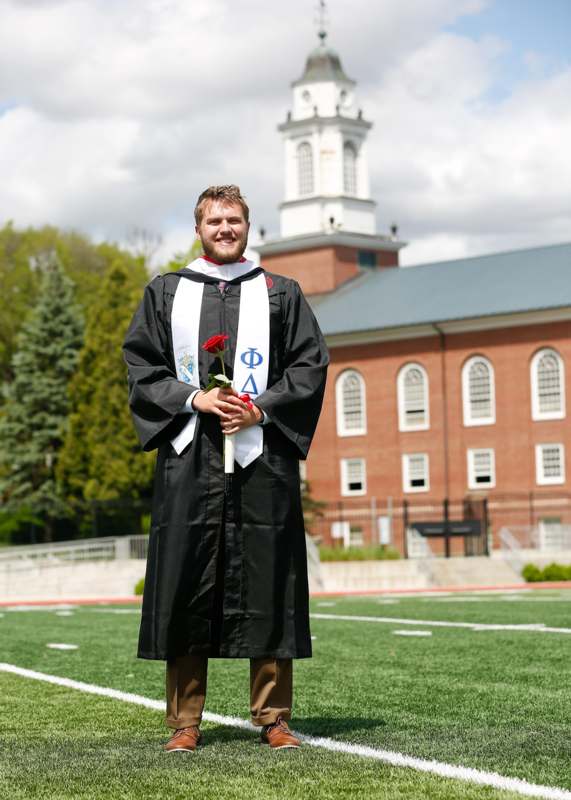 a man in a graduation gown holding a rose