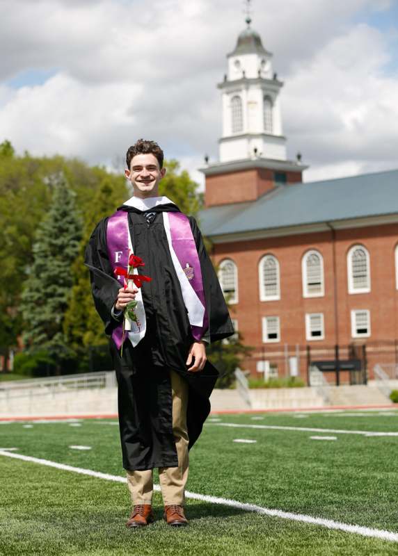 a man in a graduation gown holding flowers
