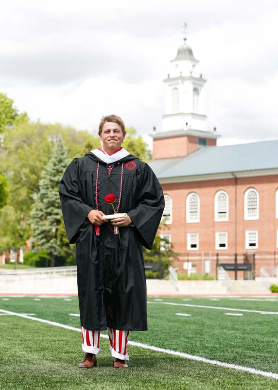 a man in a graduation gown holding a rose
