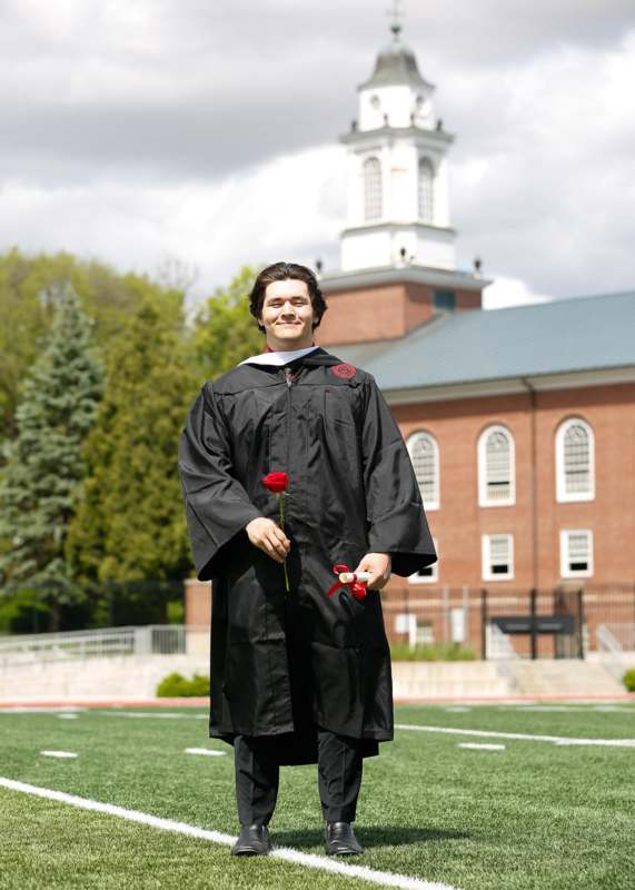 a man in a graduation gown holding a rose