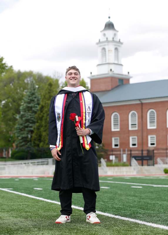 a man in a graduation gown holding a rose
