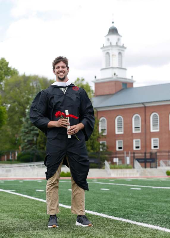 a man in a graduation gown holding a rose