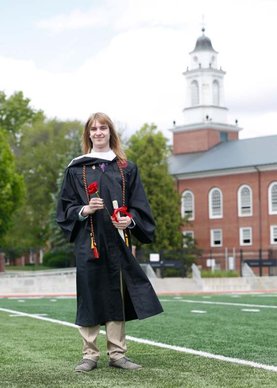 a man in a graduation gown holding a rose and a red rose