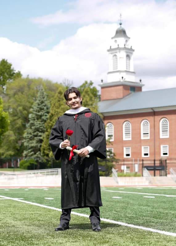 a man in a graduation gown holding a rose