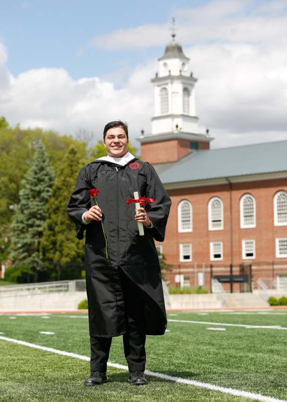 a man in a graduation gown holding roses and a sword