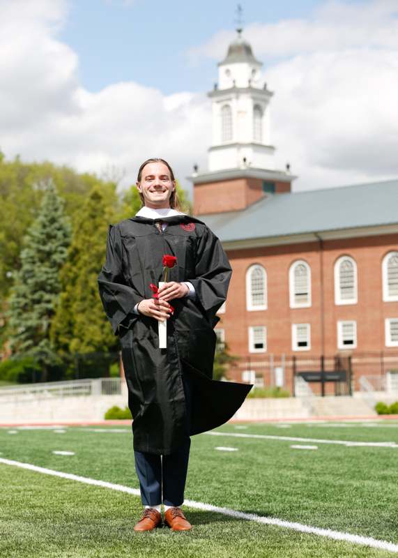 a man in a graduation gown holding a rose