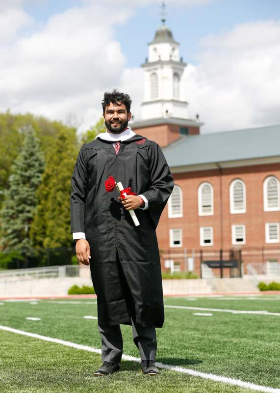 a man in a graduation gown holding a rose