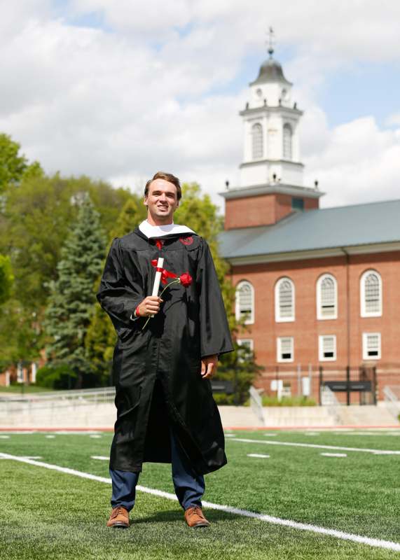 a man in a graduation gown holding a rose