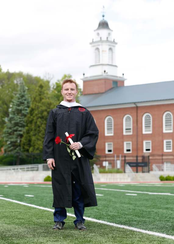 a man in a graduation gown holding a rose