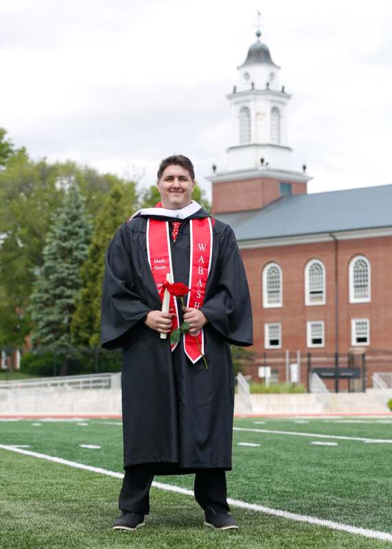 a man in a graduation gown holding a rose