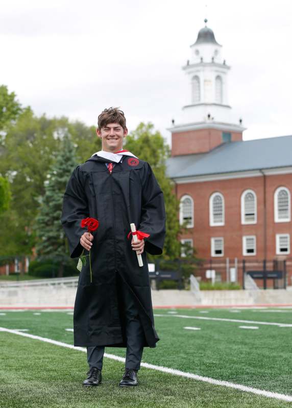 a man in a graduation gown holding flowers