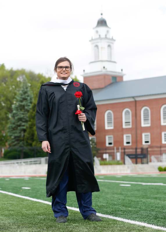 a man in a graduation gown holding a rose