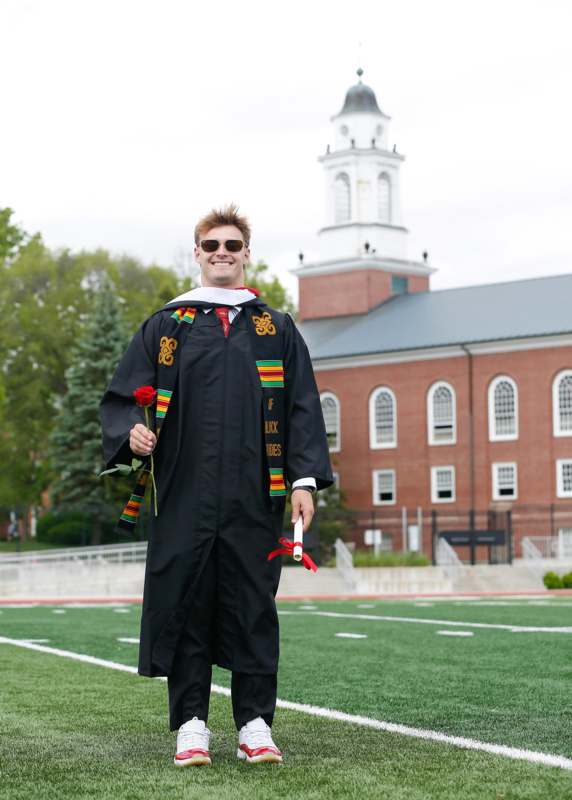 a man in a graduation gown holding a rose