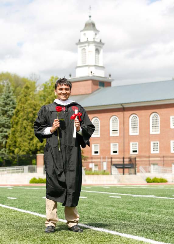a man in a graduation gown holding flowers