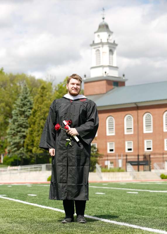 a man in a graduation gown holding a rose