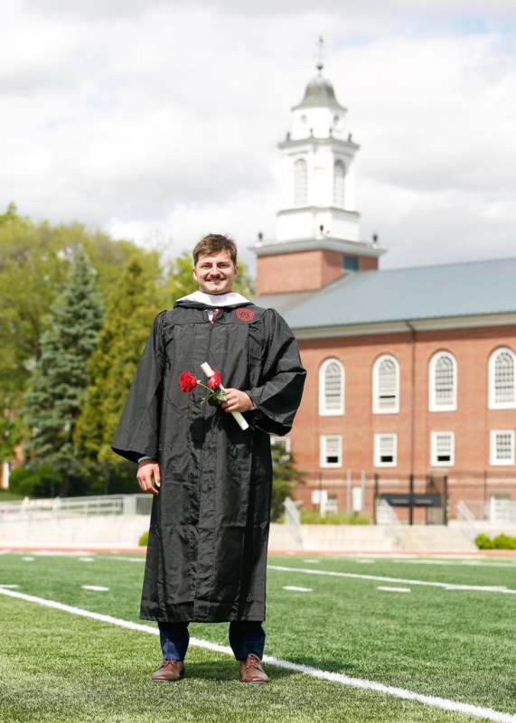 a man in a graduation gown holding flowers