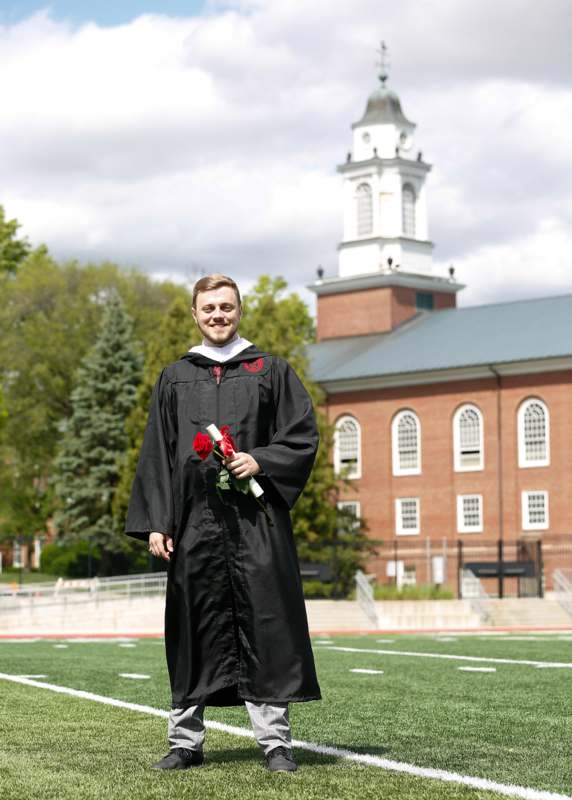 a man in a graduation gown holding a rose