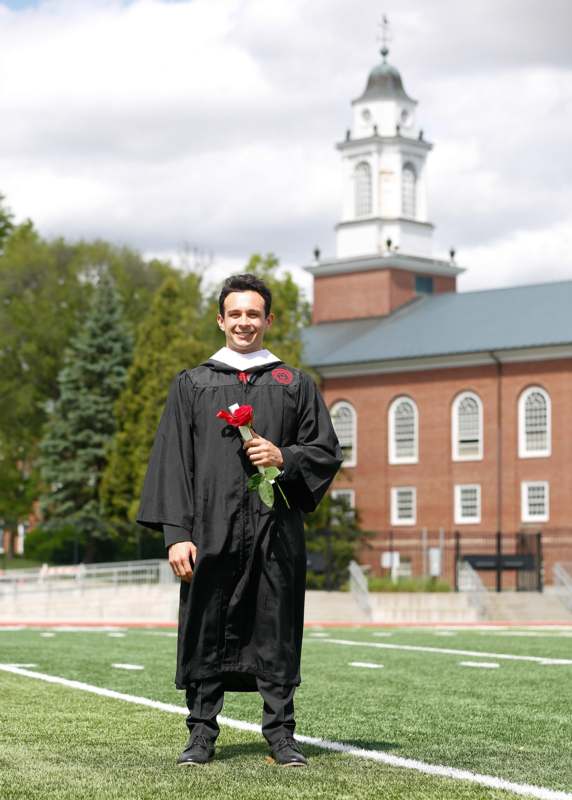 a man in a graduation gown holding a rose