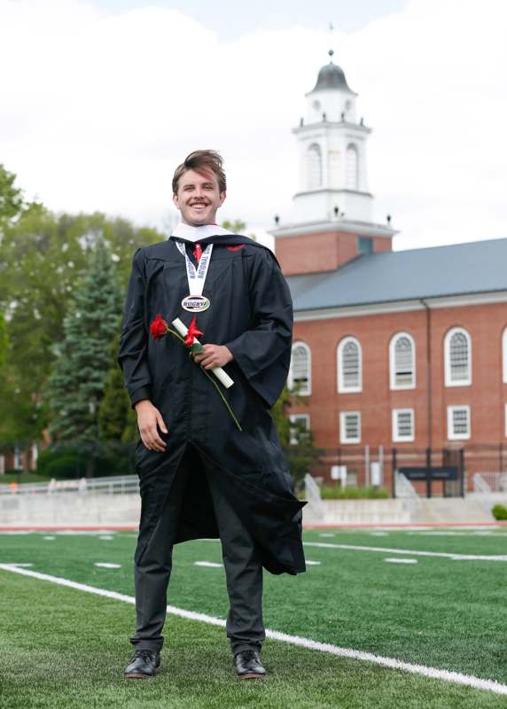 a man in a graduation gown holding flowers